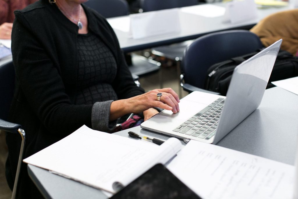 woman using a laptop on a tabletop amongst papers